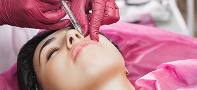 a woman laying down receiving a skin booster injection. 